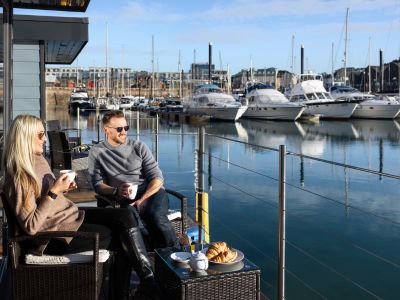 Two people enjoying a glass of wine on the deck of The Shells